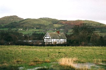 Low-lying poorly drained land along the upper Camlad, with major through routes along the valley sides, widely scattered farms, mills, and wetlands.