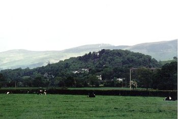 Deciduous woodland and nucleated roadside settlement with 18th- to 19th-century cottages, chapels and 20th-century housing, set around prominent, isolated limestone hill.