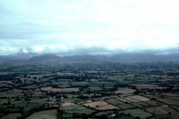 This aerial view, which looks south, gives a good impression of the mosaic of fields and scatter of small farms which characterise this low-lying, flat area. Bontnewydd (area 20) is on the left edge of the shot, with the mountains behind.
