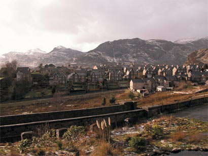 A horseshoe-shaped settlement built on a natural shelf near the break of slope at the head of a valley, surrounded by slate-rubble tips; the largest town in the former county of Merioneth. A number of sub-medieval farmhouses survive near the break of slope, together with dwellings associated with nineteenth century smallholdings carved out of the farms.