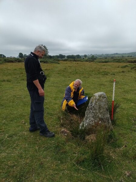 A Dyfed-Powys Police officer and a Cadw field monument warden examining a standing stone at Gors Fawr stone circle during the site assessment.